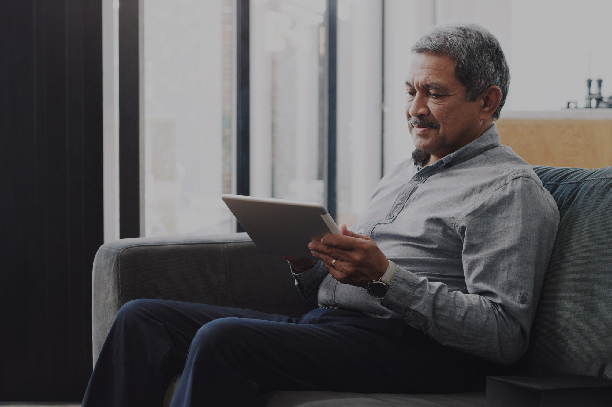 Older man reading a tablet.